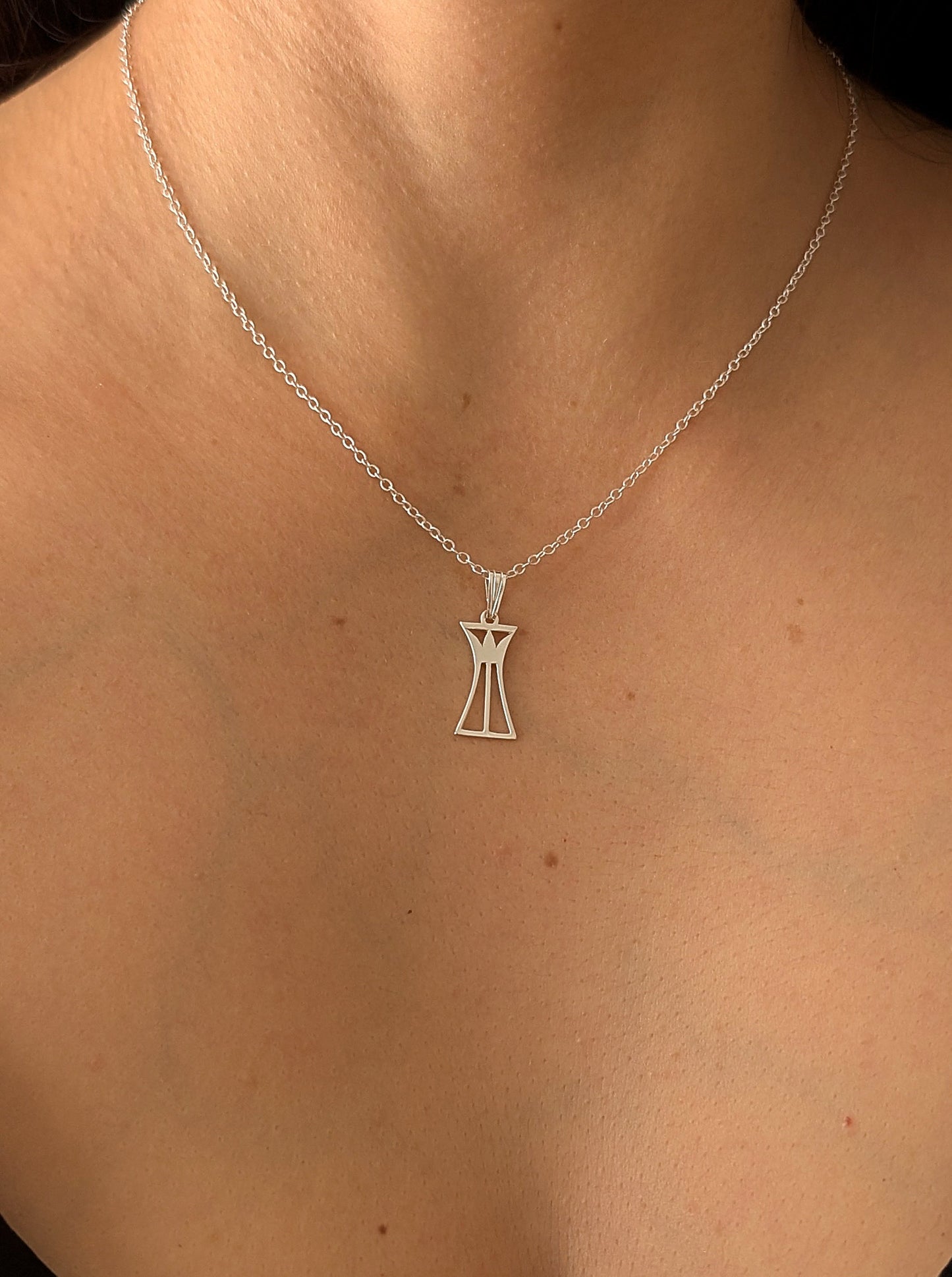Silver necklace with a lotus column pendant on a woman's neck