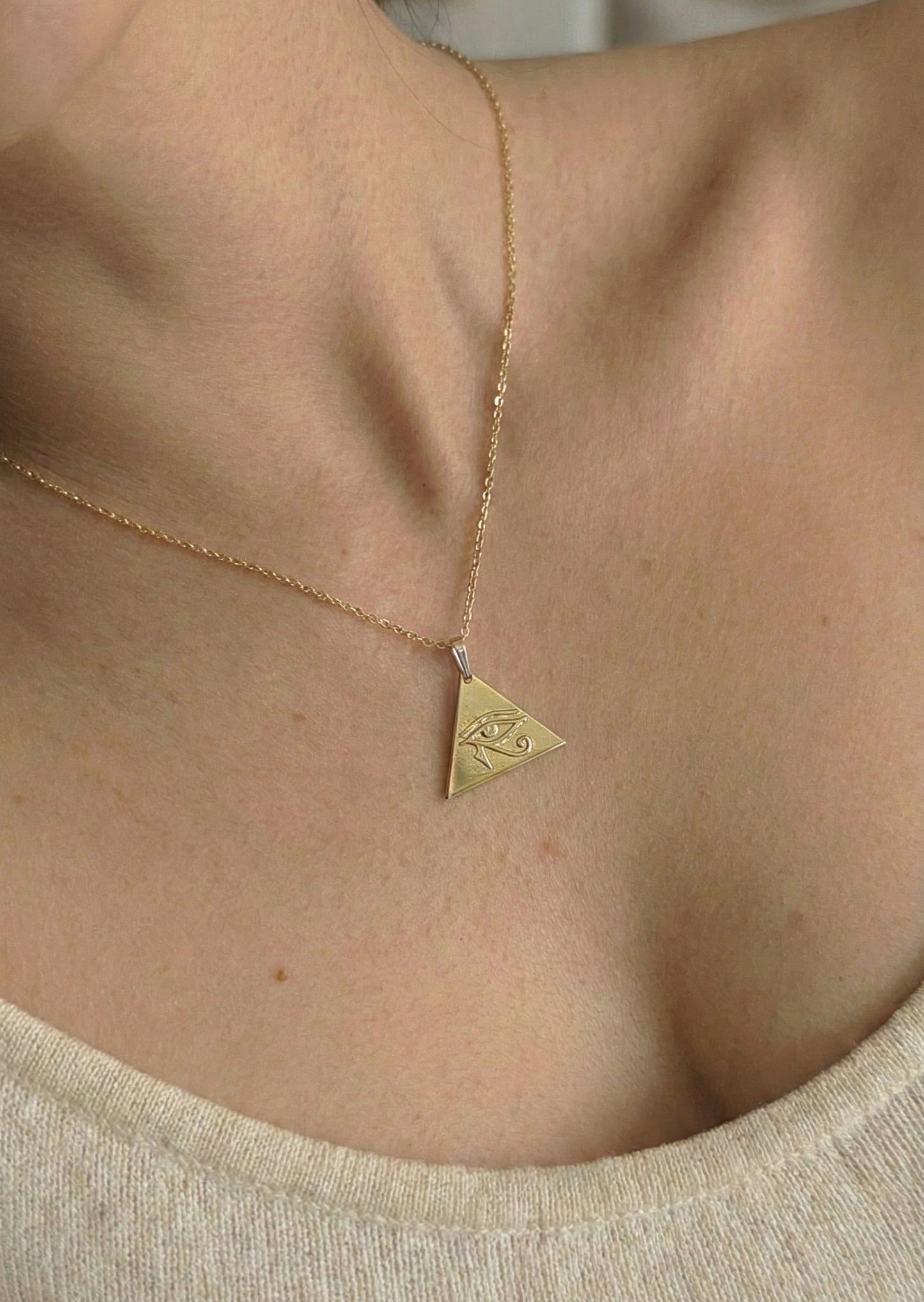 close up of gold eye of horus necklace worn by woman