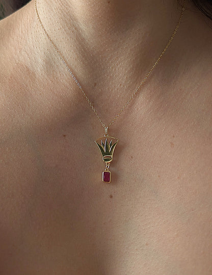 Gold necklace with a lotus pendant featuring a red gemstone on a woman's neck