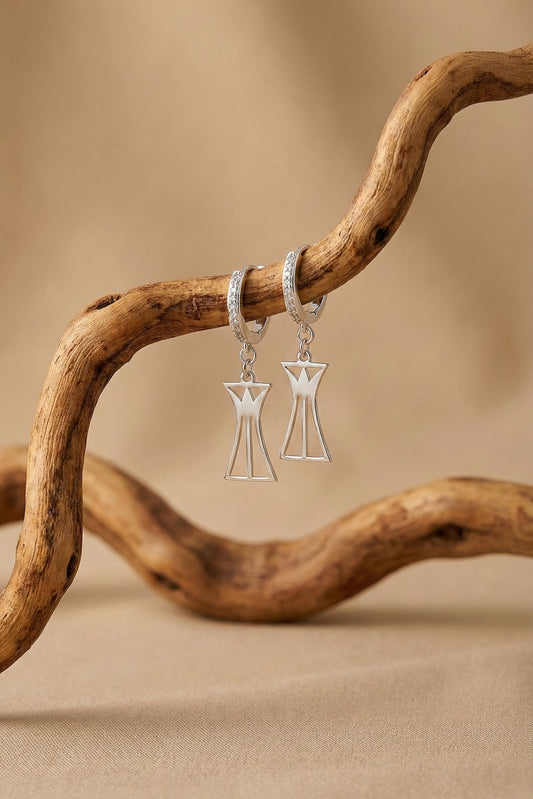 Sterling silver lotus column earrings with pavé huggie hoops on wood branch