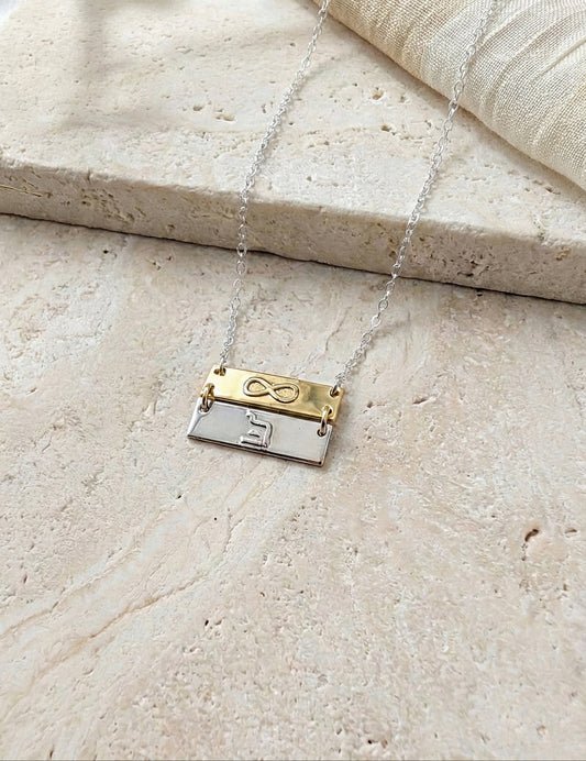 Infinity and eternity necklace for women in gold and silver on stone background