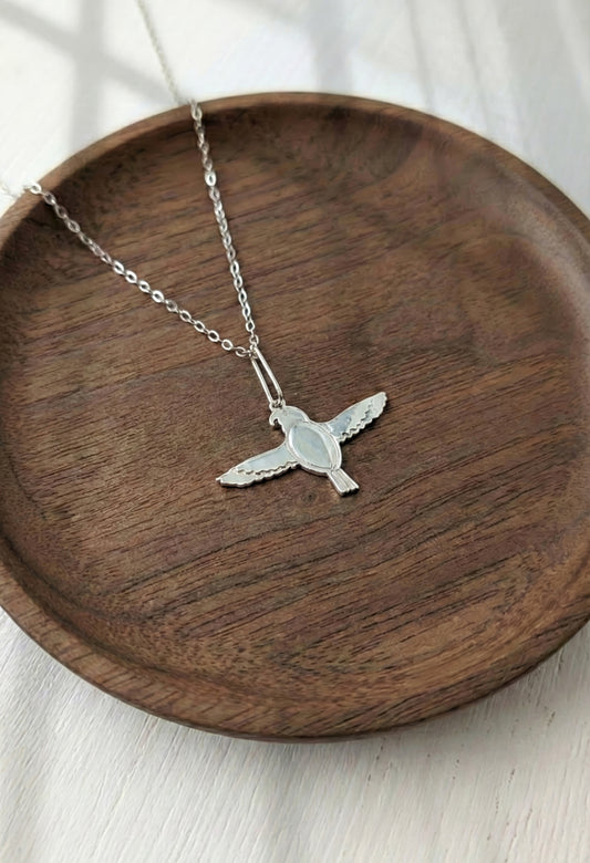 Sterling silver falcon pendant necklace on wooden background
