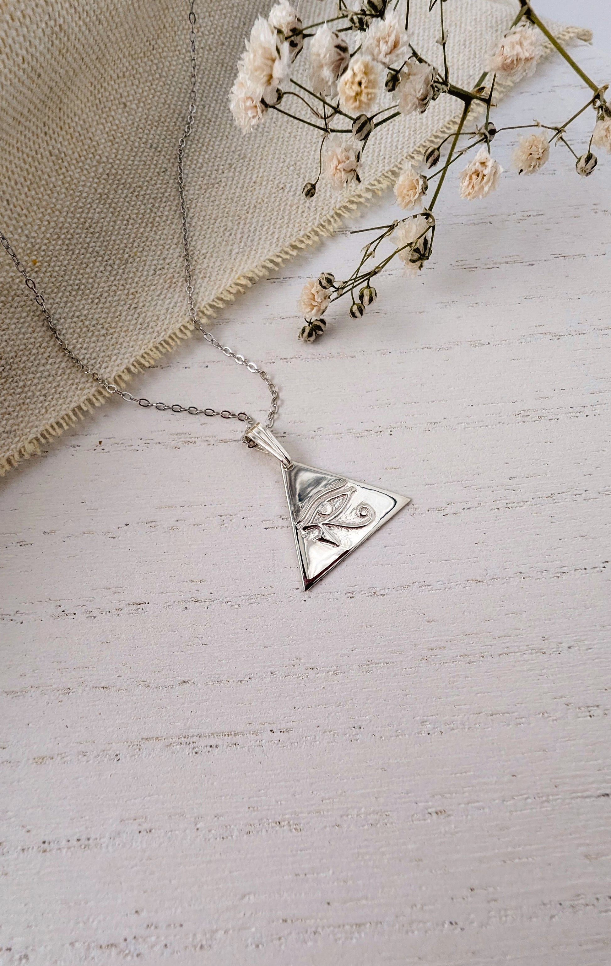 silver eye of horus pendant on wooden background