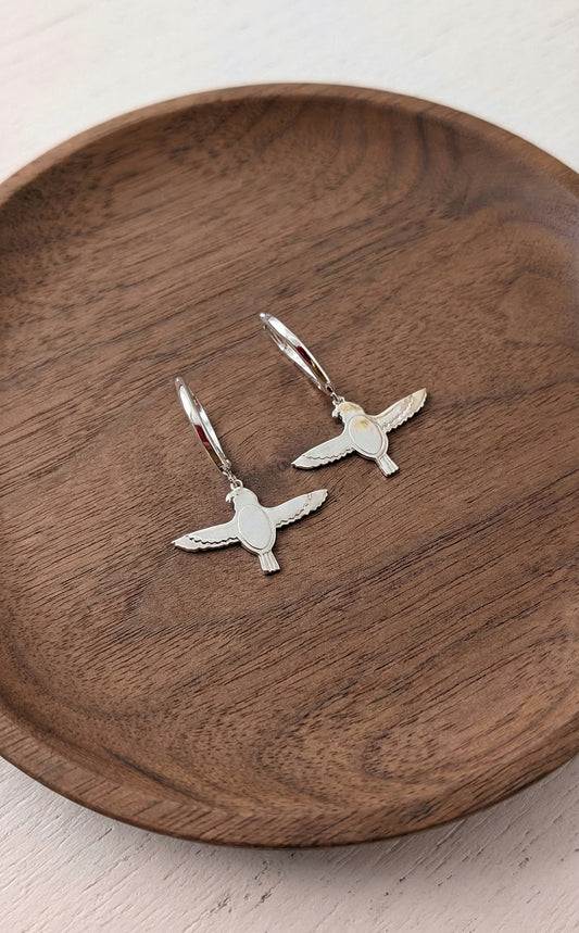 Sterling silver falcon drop earrings on wooden background