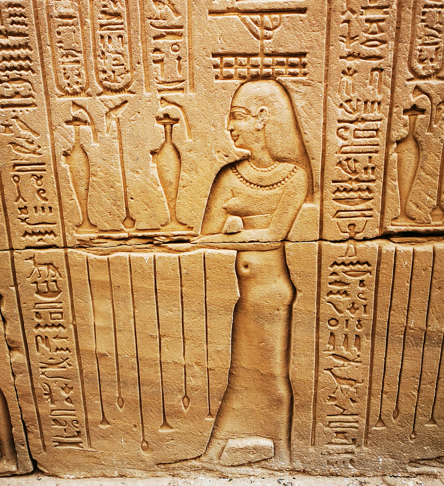Carved relief of a figure with hieroglyphics on a stone wall