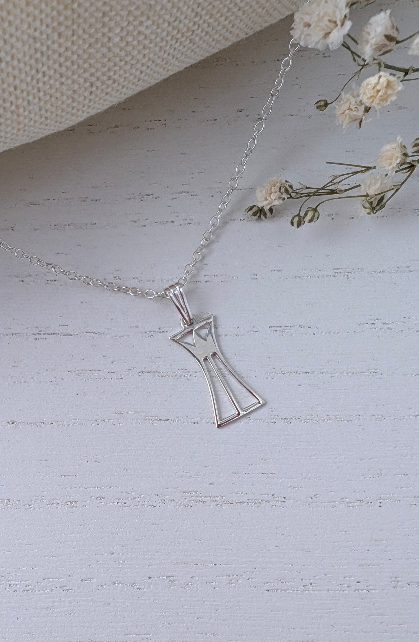 silver lotus column necklace on a wooden surface