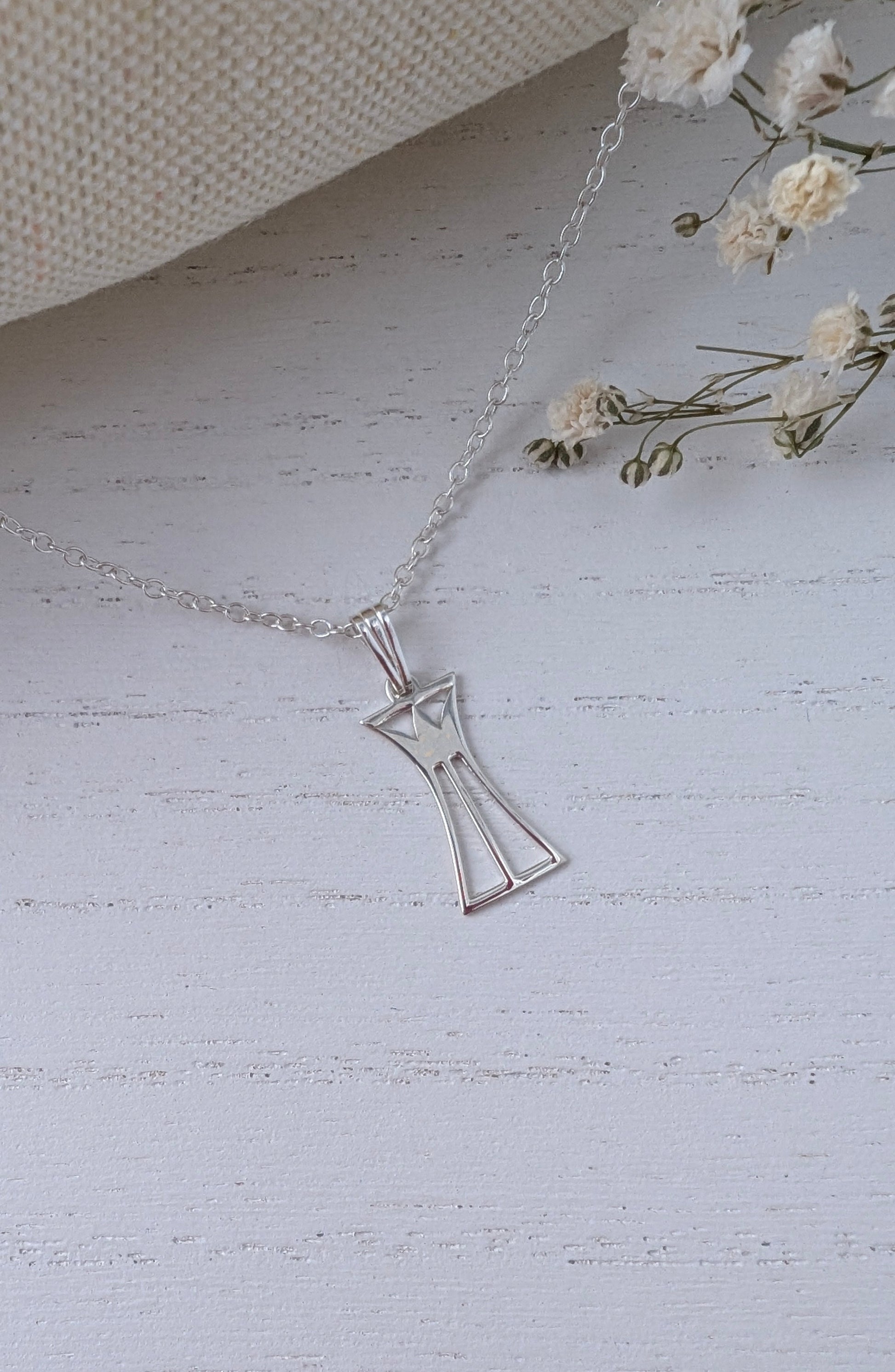 silver lotus column necklace on a wooden surface