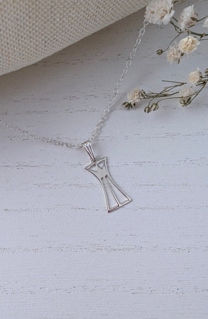 silver lotus column necklace on a wooden surface