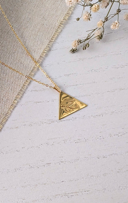 gold eye of horus pendant on wooden background