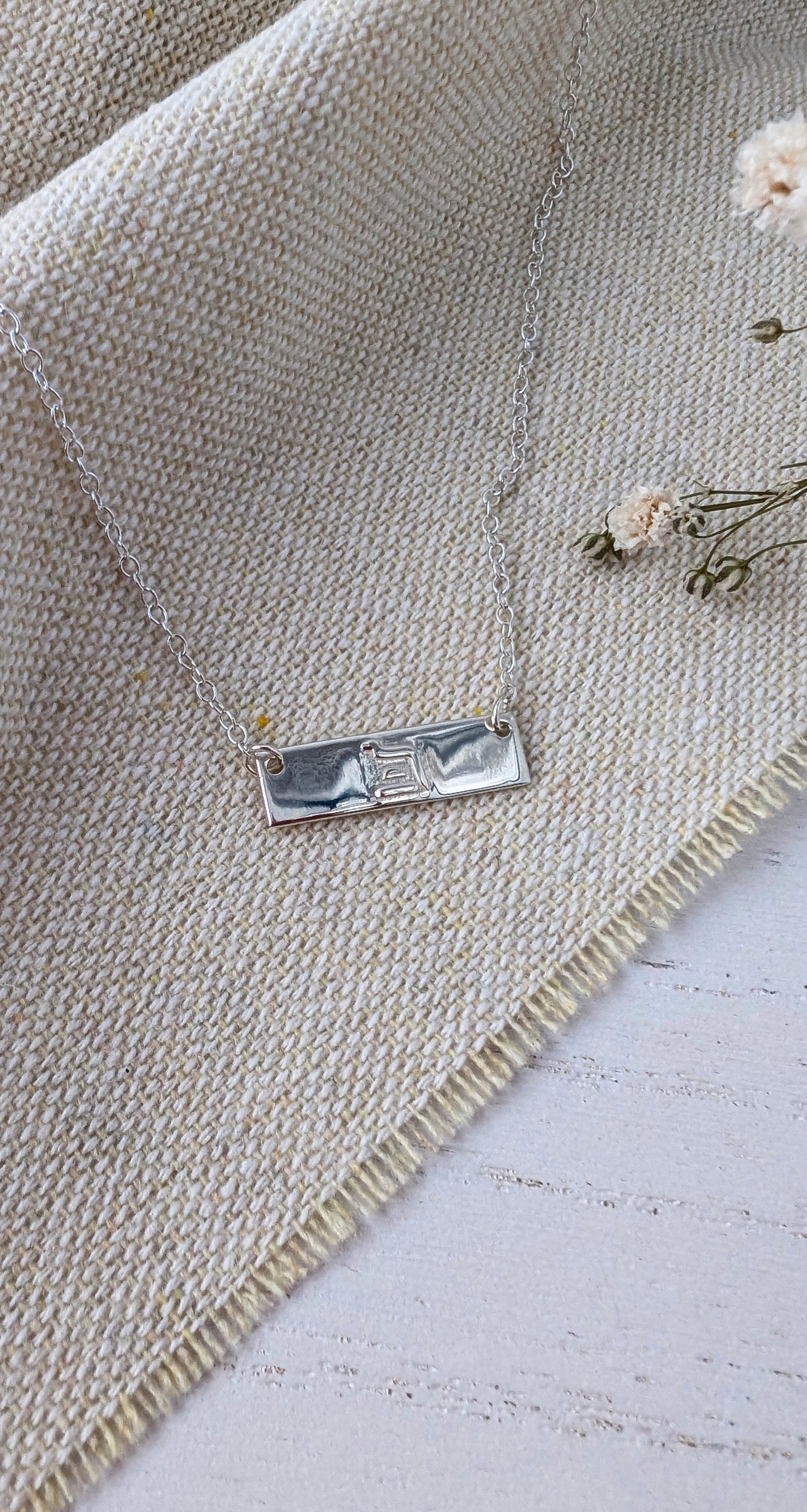 silver eternity bar necklace on beige linen fabric