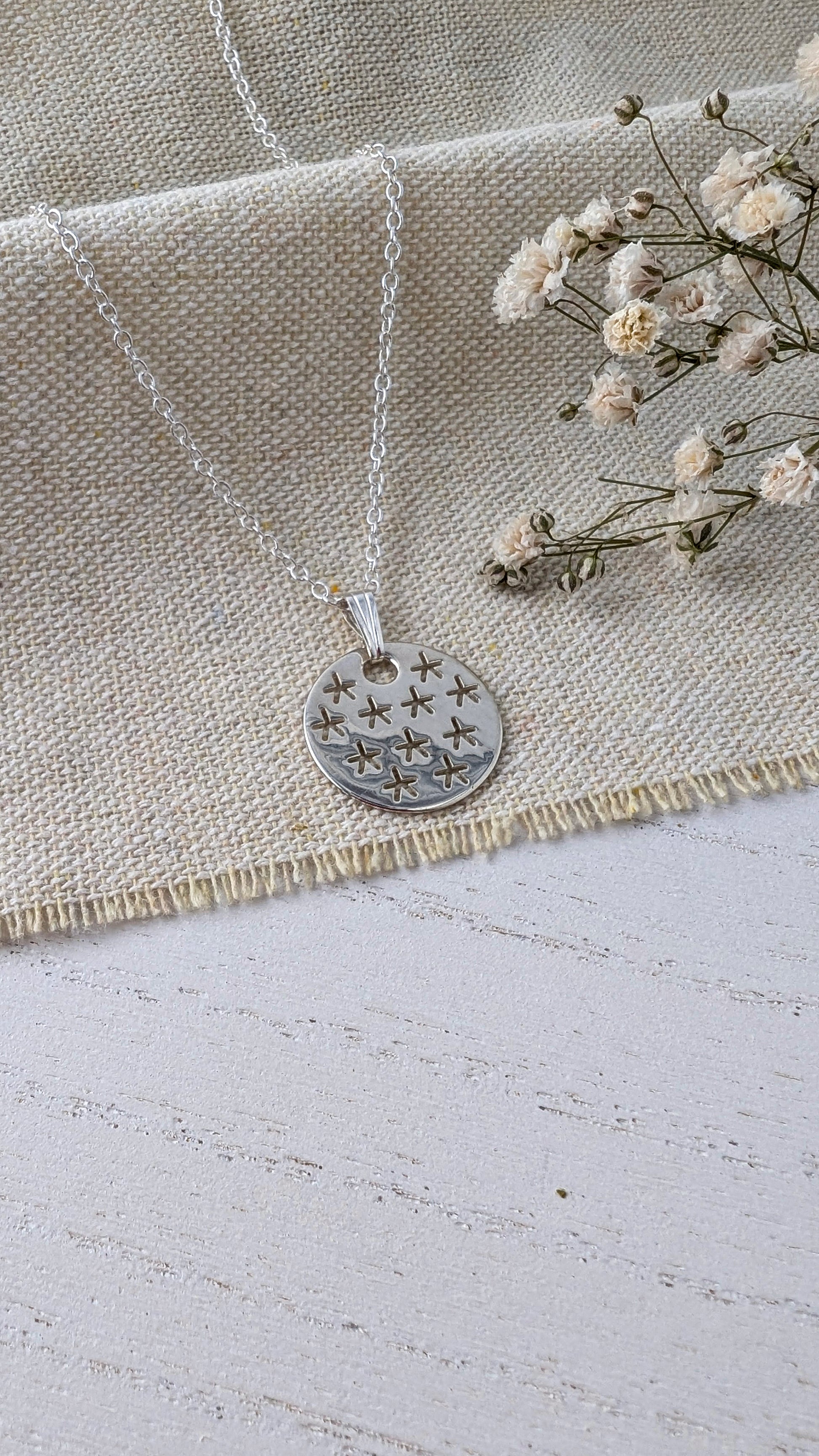 silver stars necklace on beige linen fabric