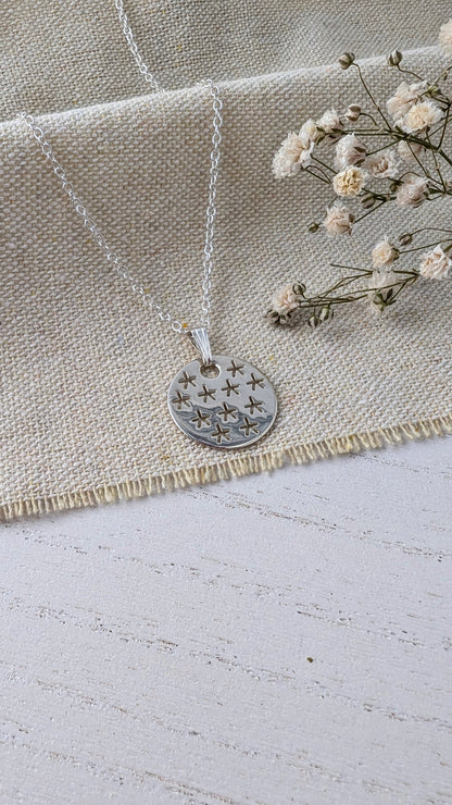 silver stars necklace on beige linen fabric