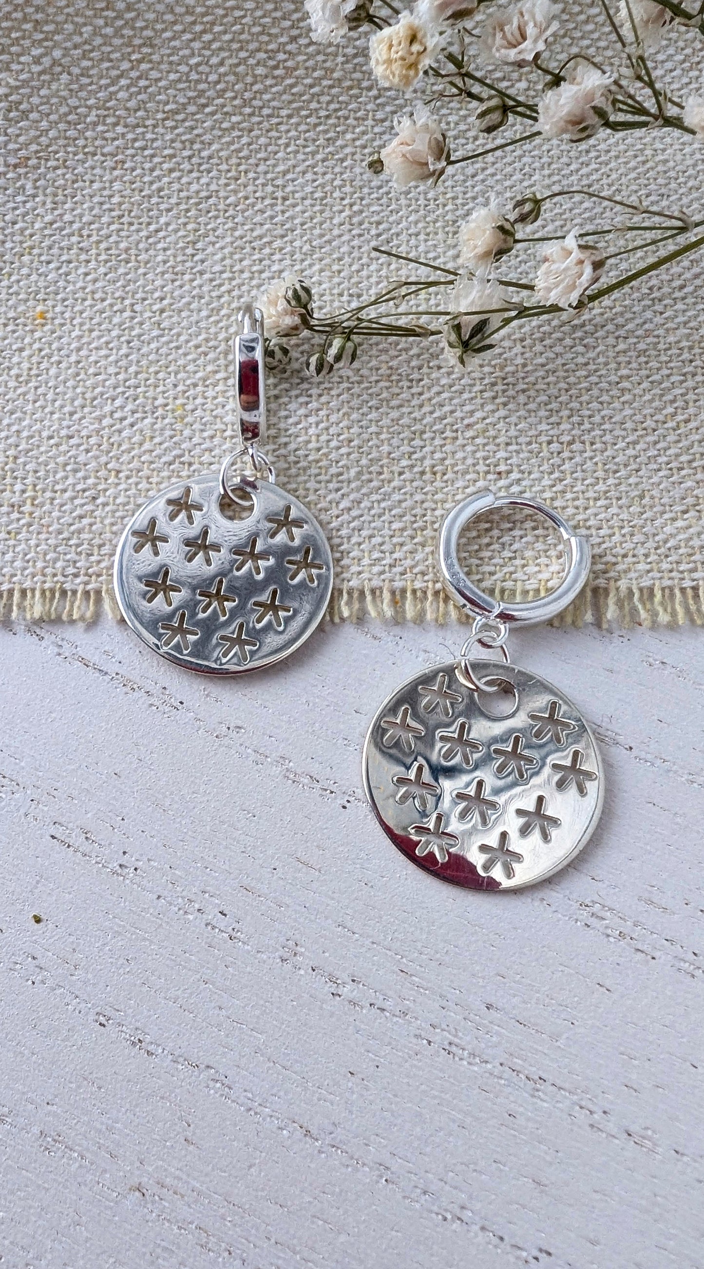 silver stars earrings on beige wooden surface