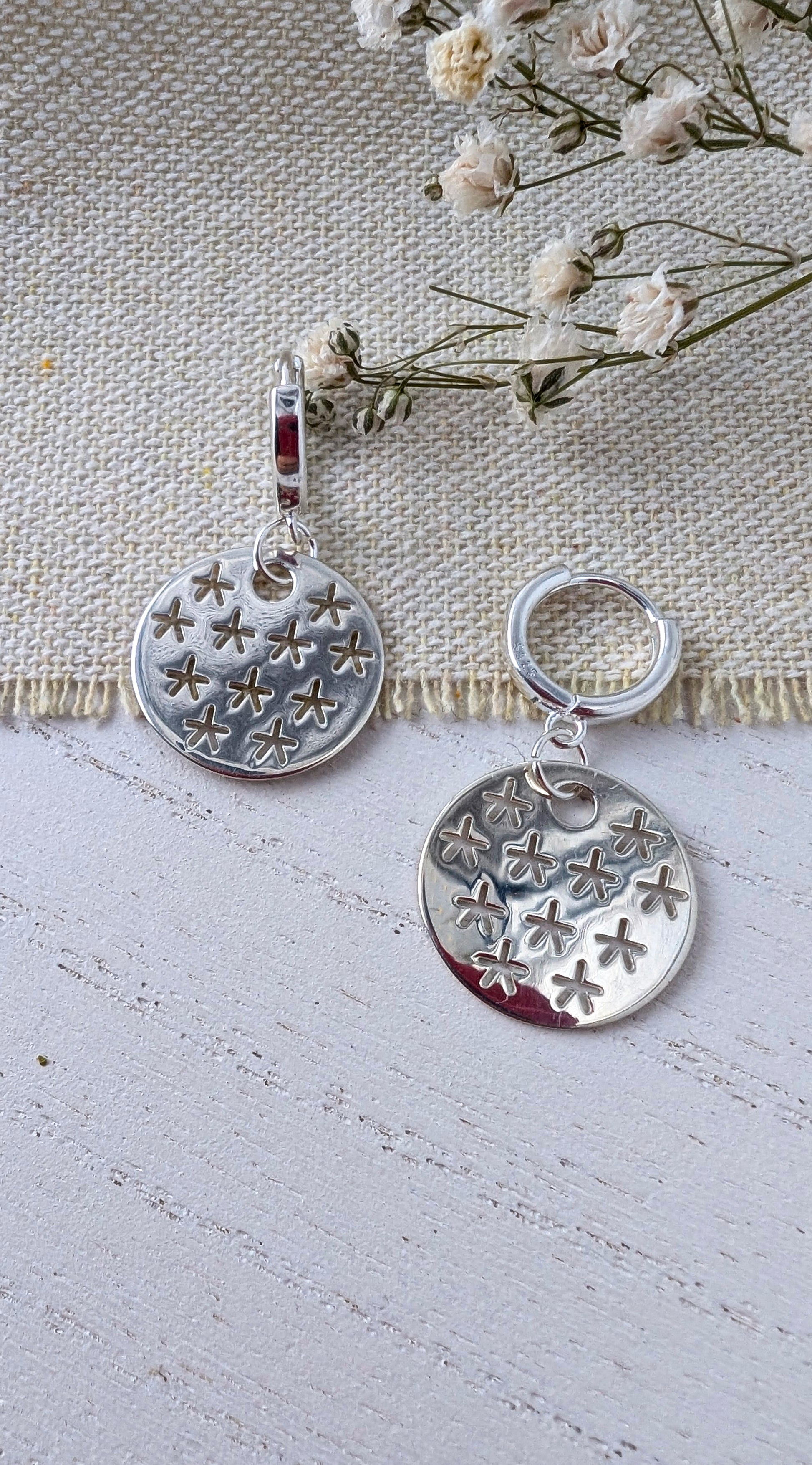 silver stars earrings on beige wooden surface