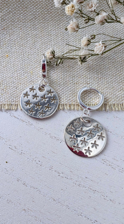 silver stars earrings on beige wooden surface