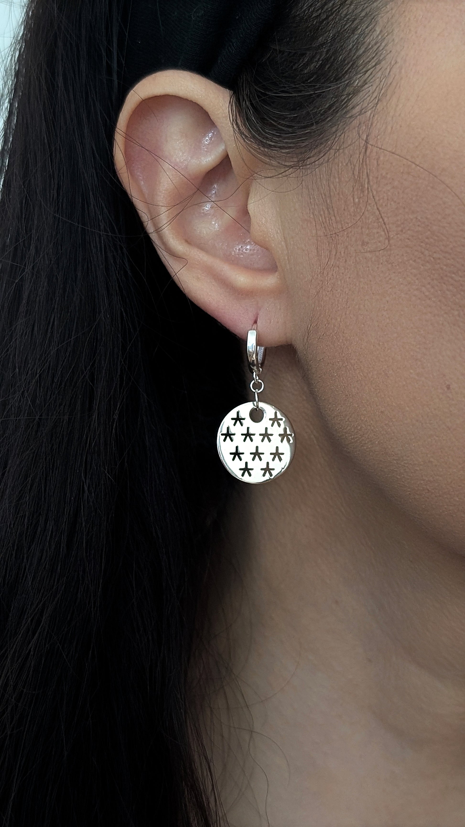 silver earring with stars design worn by woman
