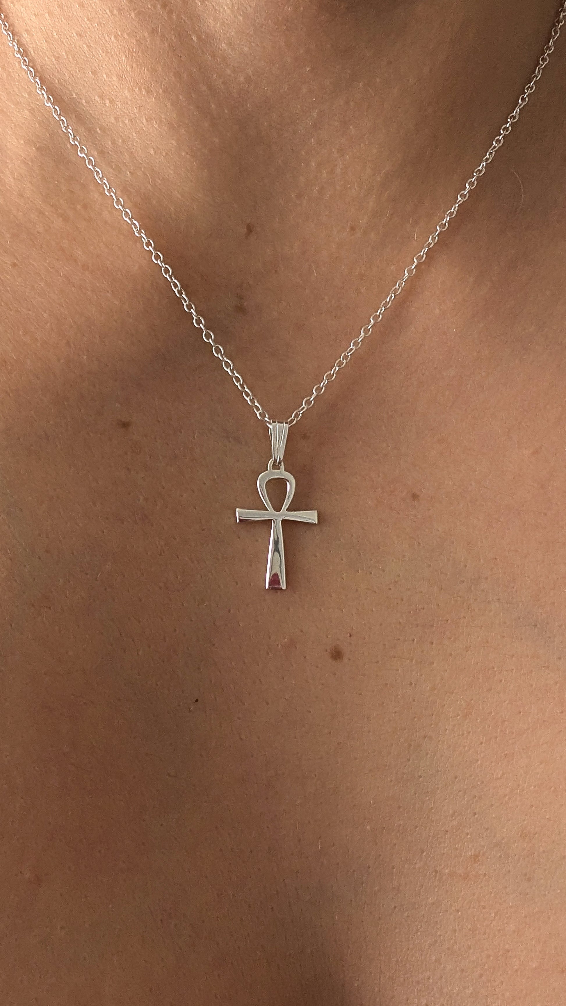 Silver necklace with an ankh pendant on a person's neck