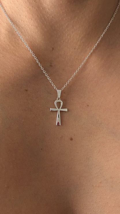 Silver necklace with an ankh pendant on a person's neck