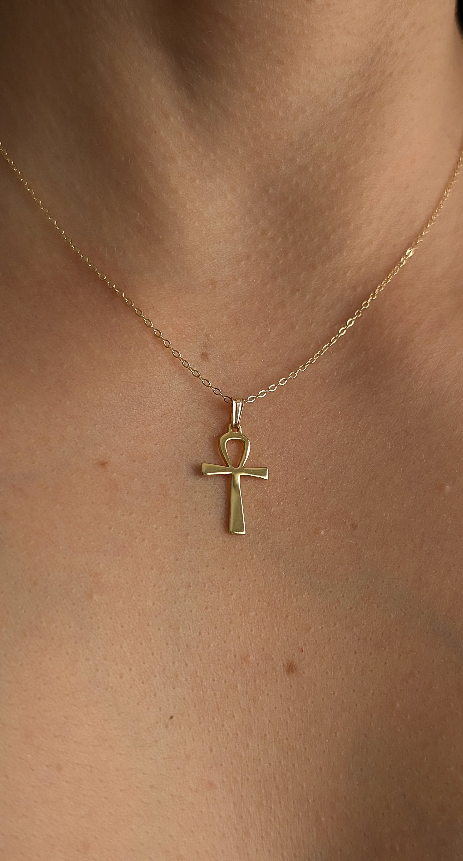 Gold necklace with a ankh pendant on a person's neck