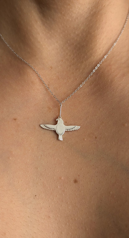 close up of falcon necklace worn by woman
