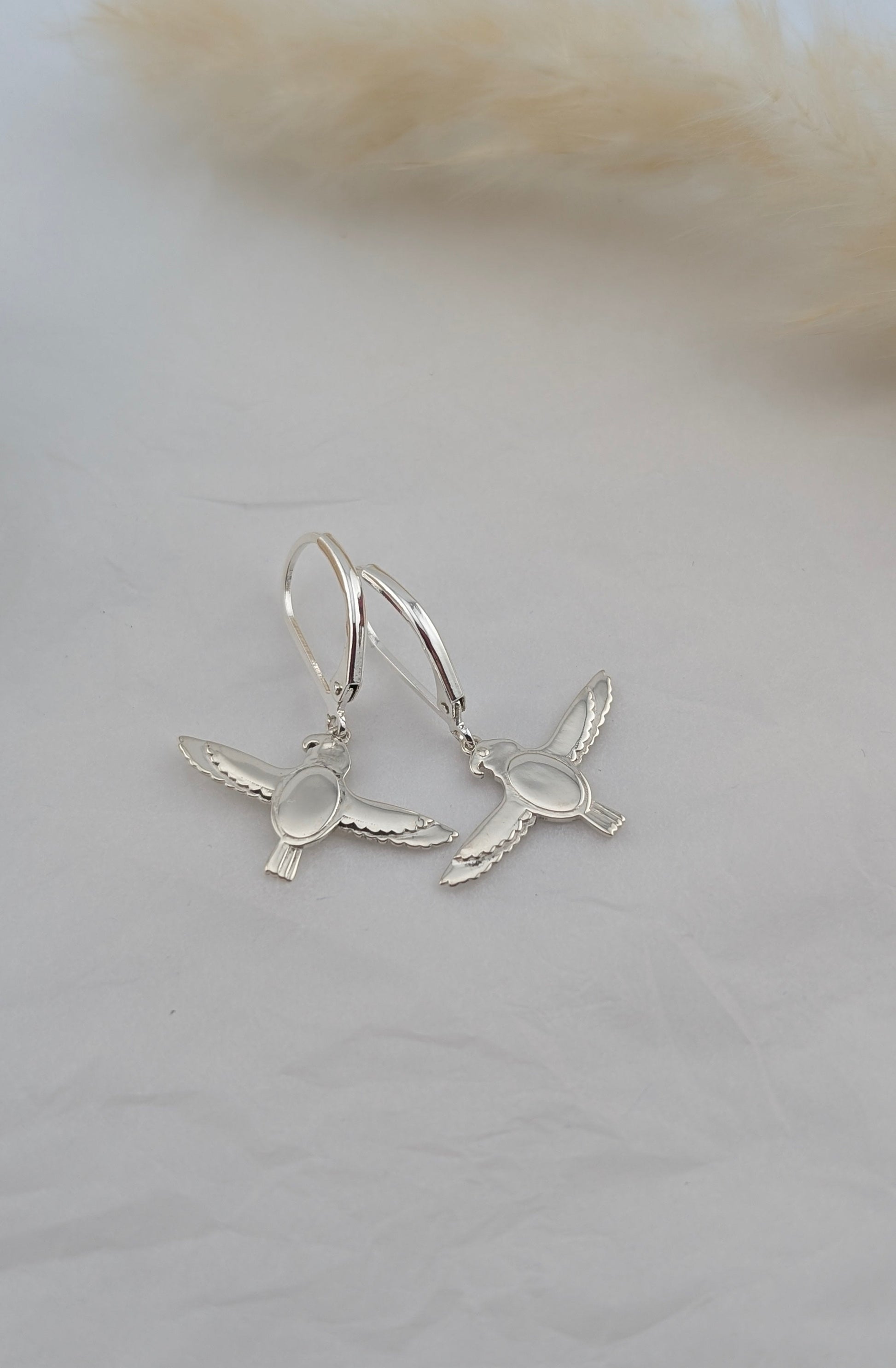silver falcon earrings on white background