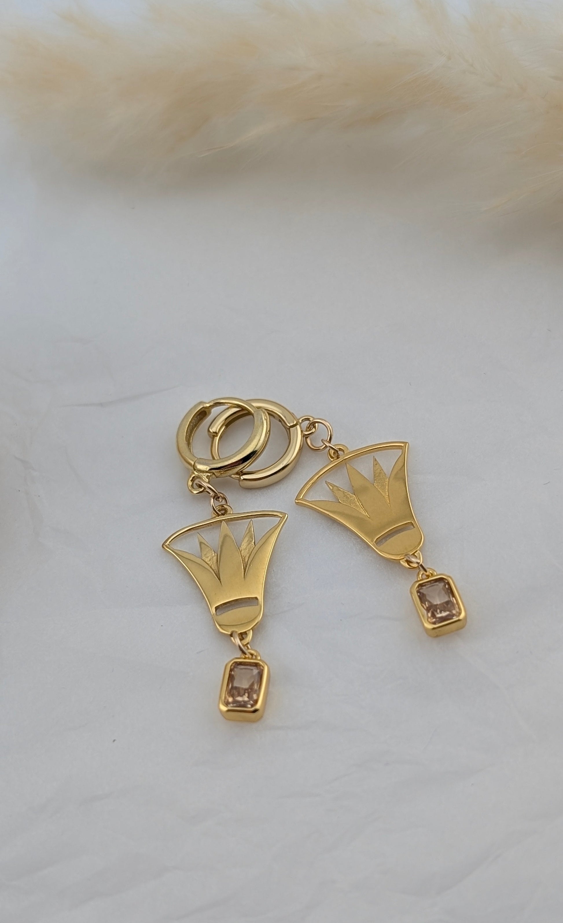 Gold lotus earrings with geometric designs on a white surface