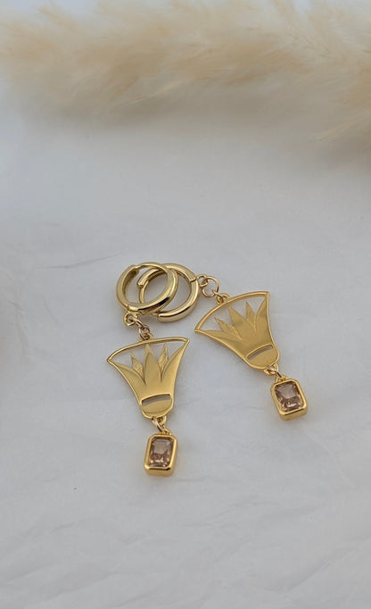 Gold lotus earrings with geometric designs on a white surface