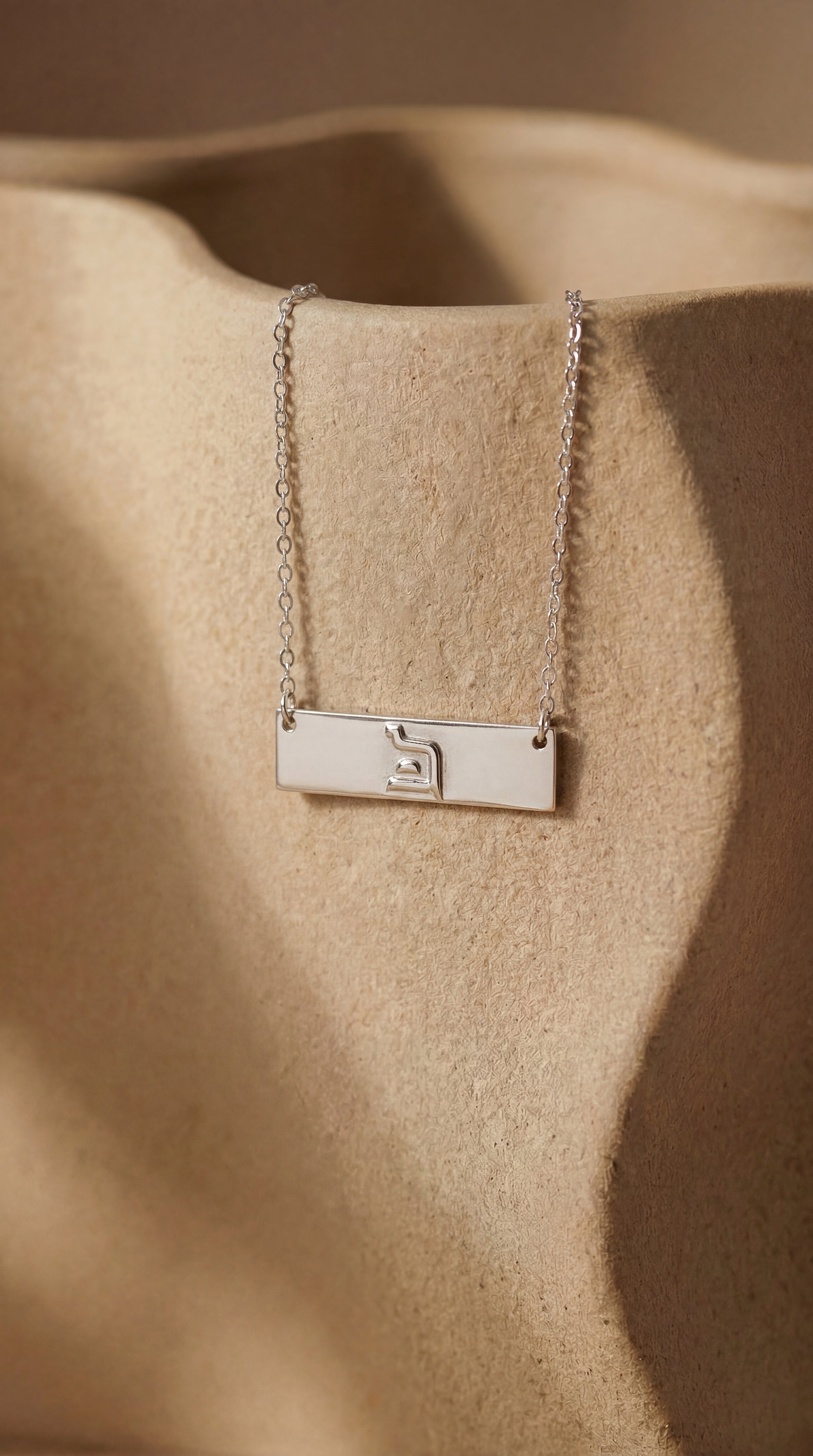 silver eternity bar necklace on beige ceramic surface