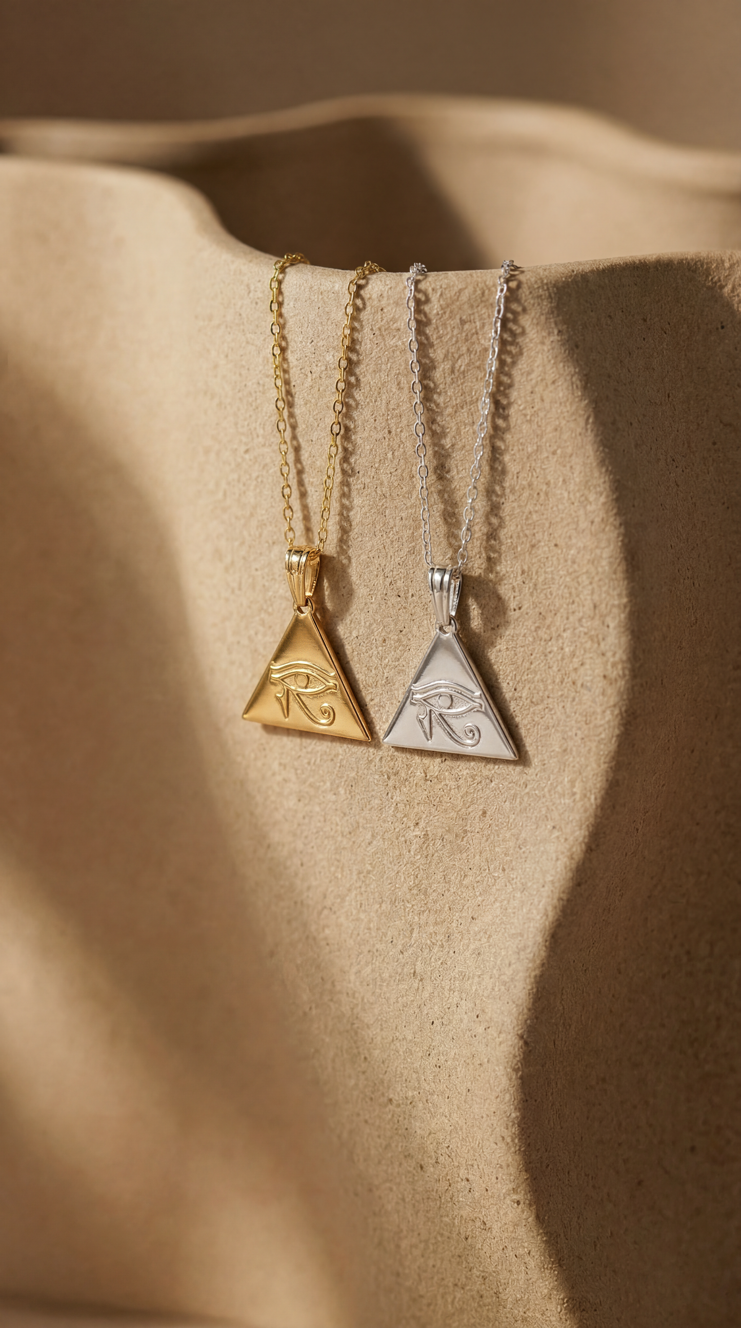 silver and gold necklaces with eye of horus pendant on ceramic surface