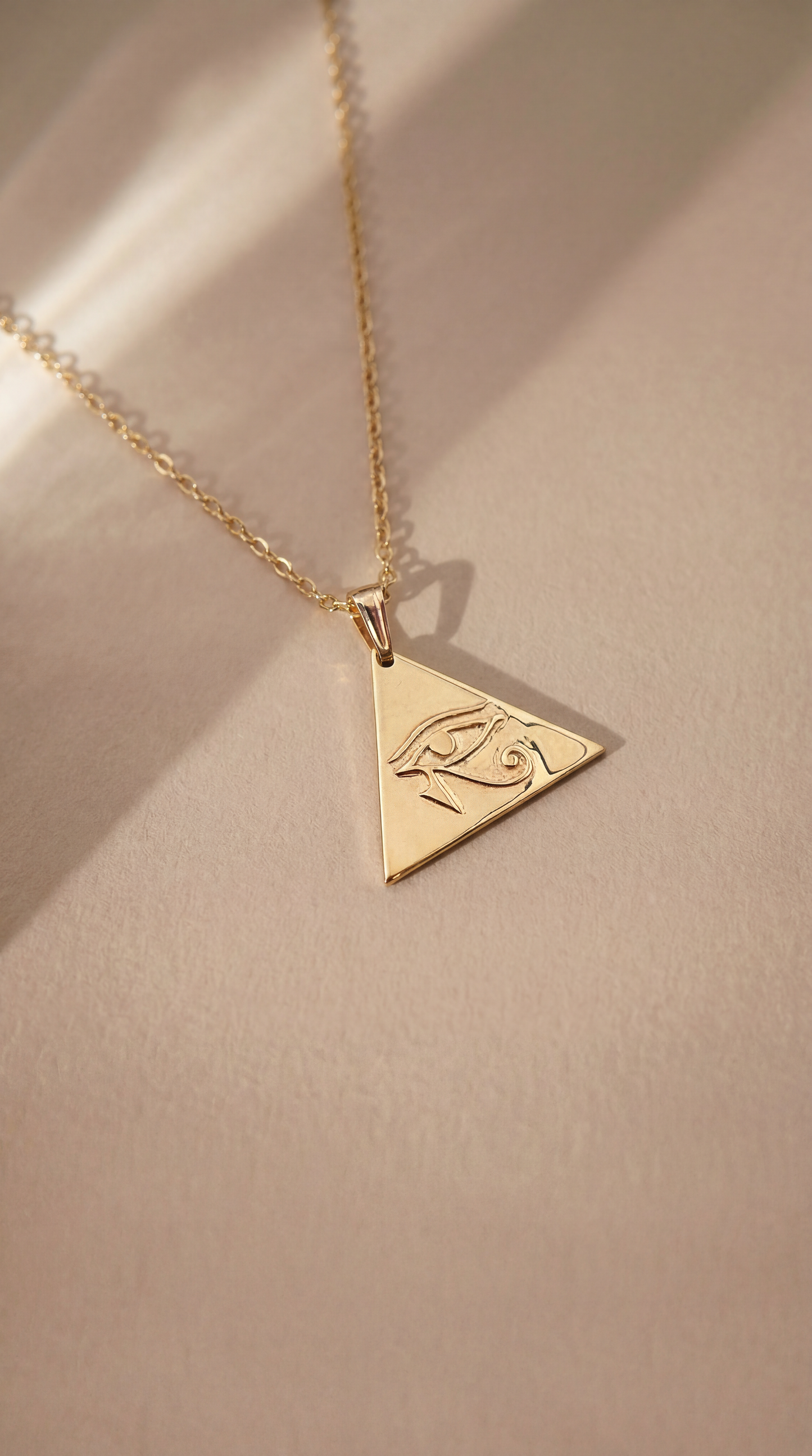 gold eye of horus necklace on beige background