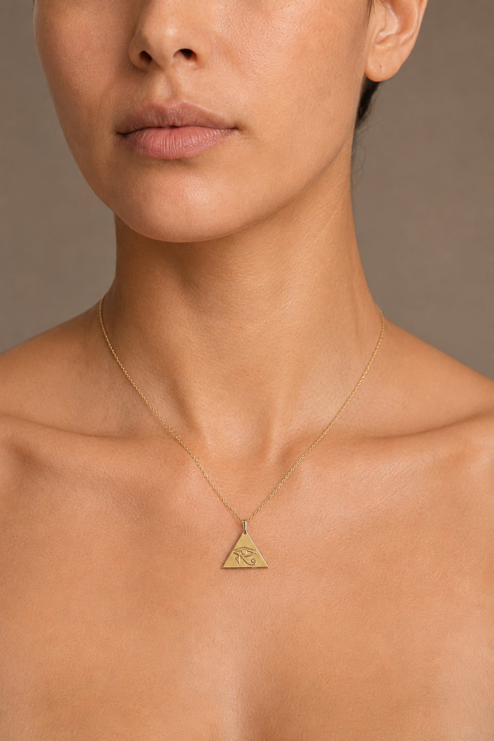 close up of gold eye of horus pendant necklace on woman 