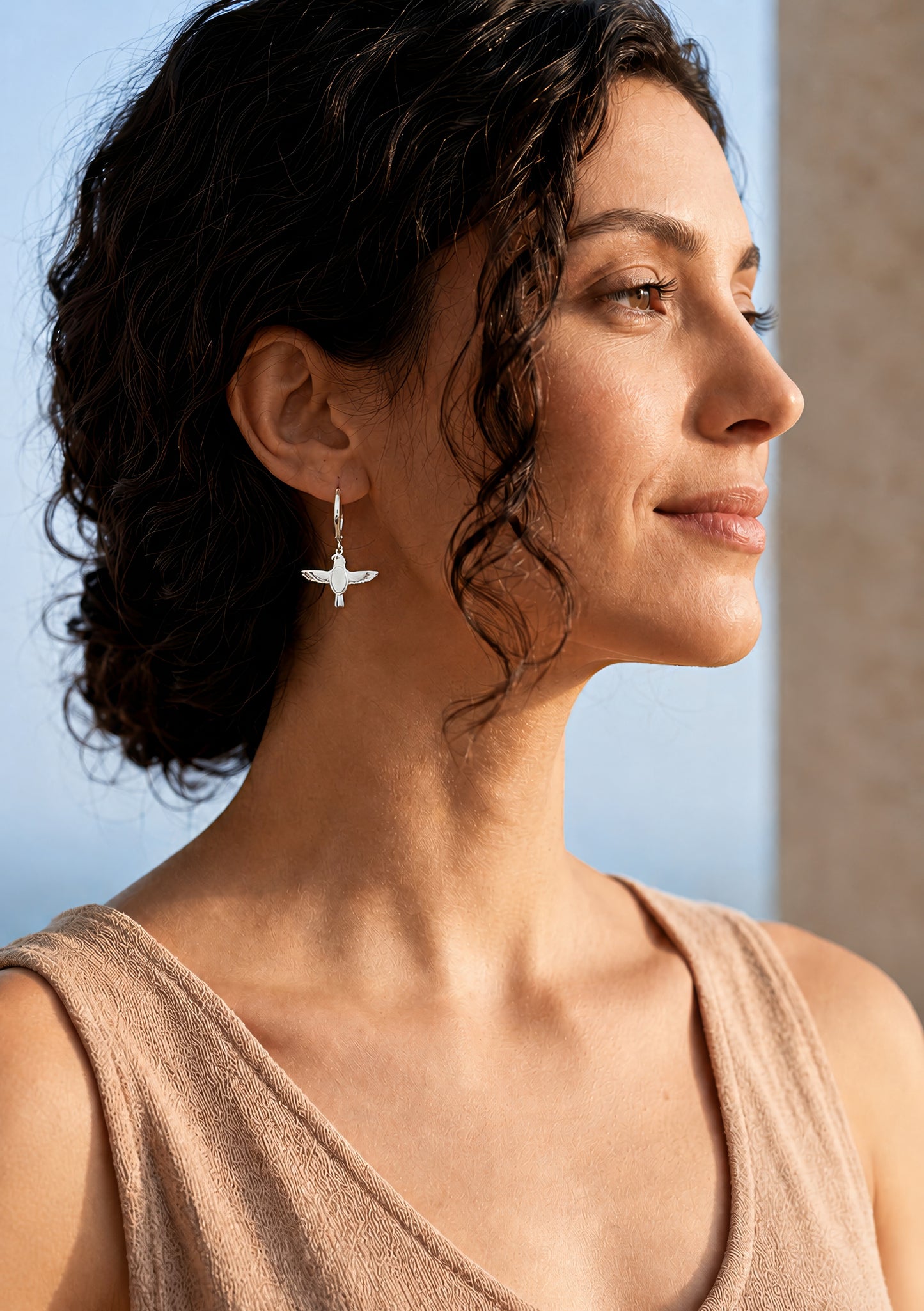 silver falcon earring worn by woman