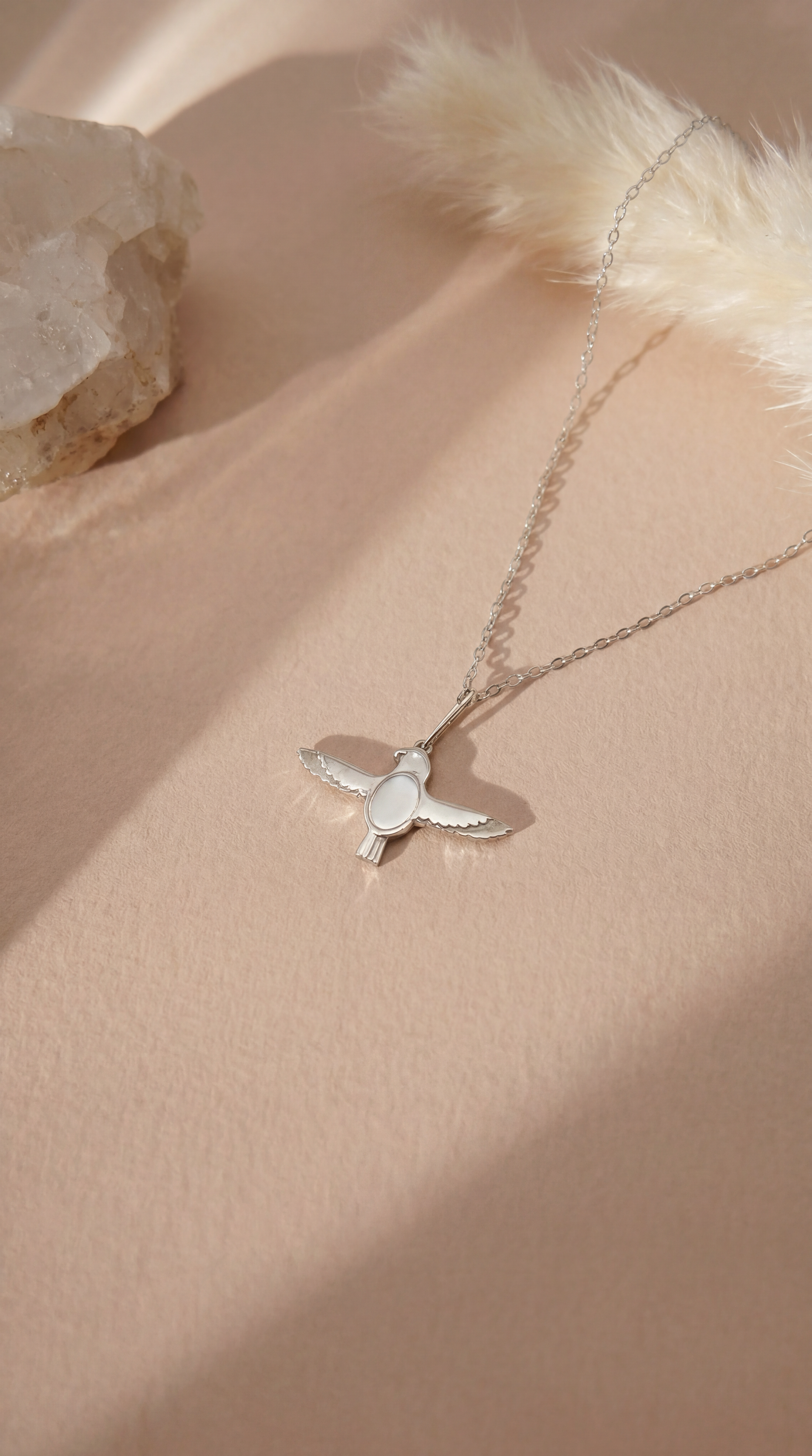 silver necklace with falcon pendant on beige background