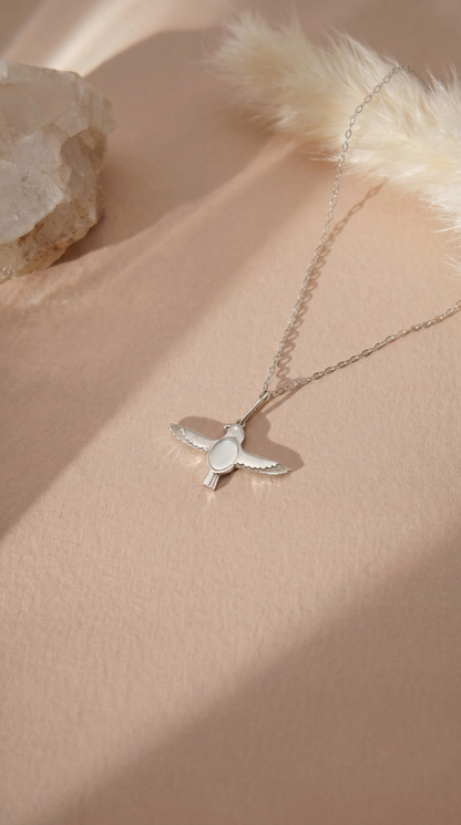 silver necklace with falcon pendant on beige background