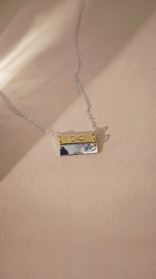 double bar necklace with infinity and eternity symbols on beige background
