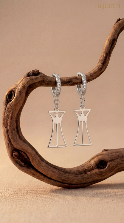 Silver lotus column earrings hanging from a branch with a beige background
