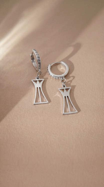Silver hoop earrings with geometric lotus column pendant on a beige background