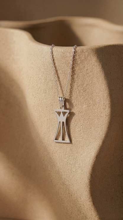 Silver necklace with a lotus column pendant on a beige fabric background