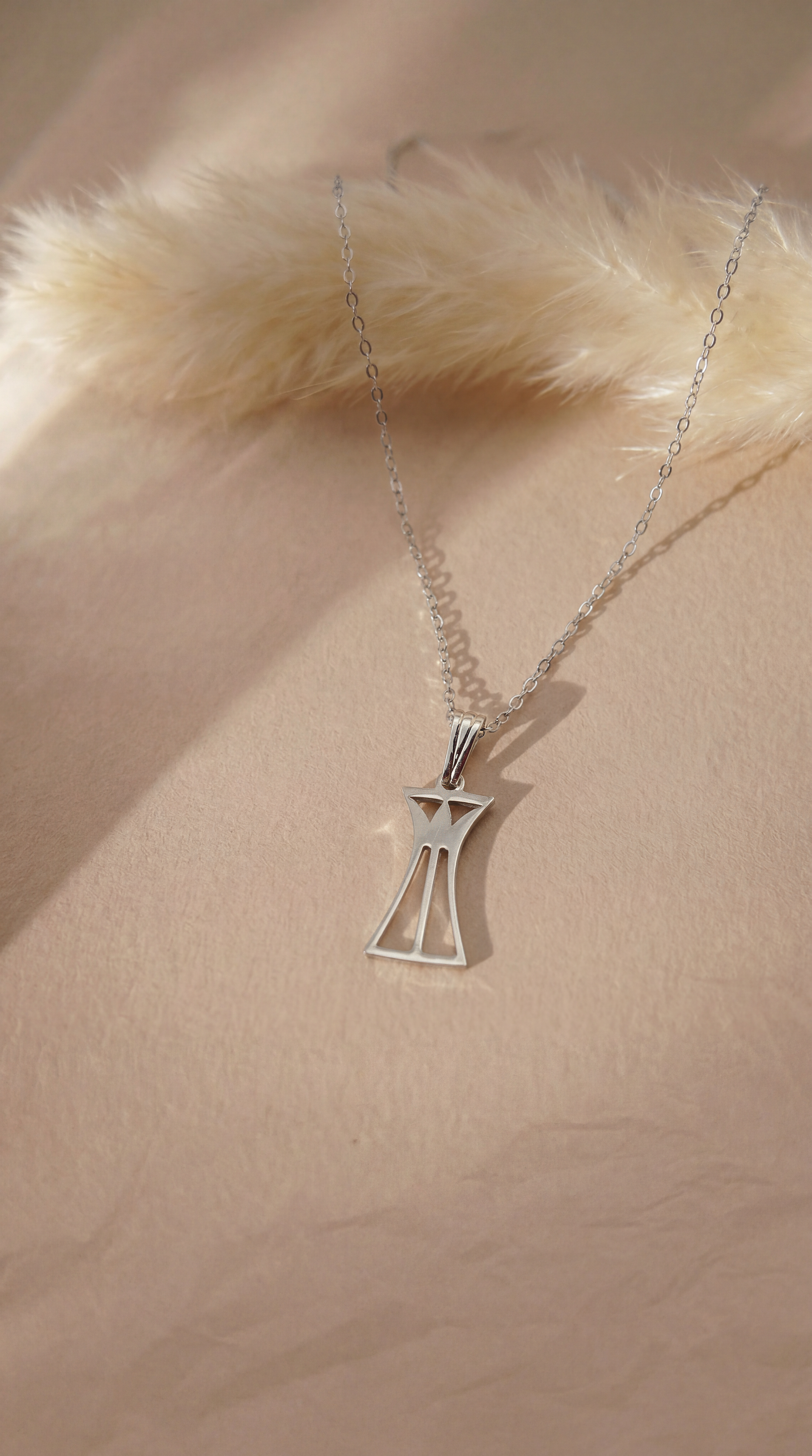 Silver lotus column necklace on a beige background