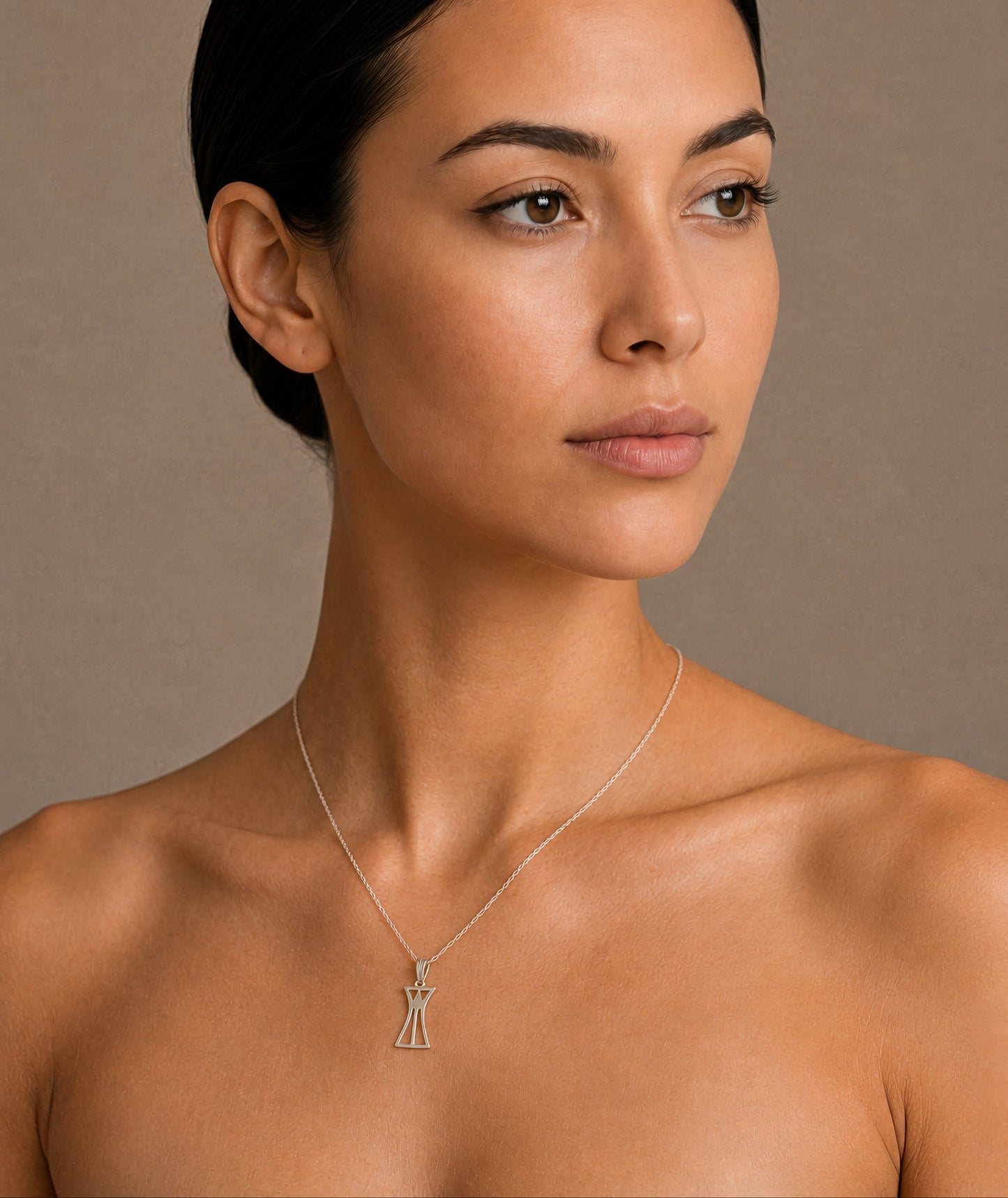 Woman wearing a necklace with a lotus column pendant against a neutral background