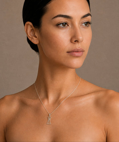 Woman wearing a necklace with a lotus column pendant against a neutral background
