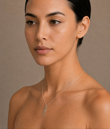 Woman wearing a silver lotus column necklace against a neutral background