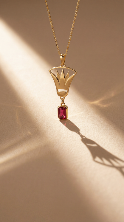 Gold lotus necklace with a red gemstone pendant on a beige background