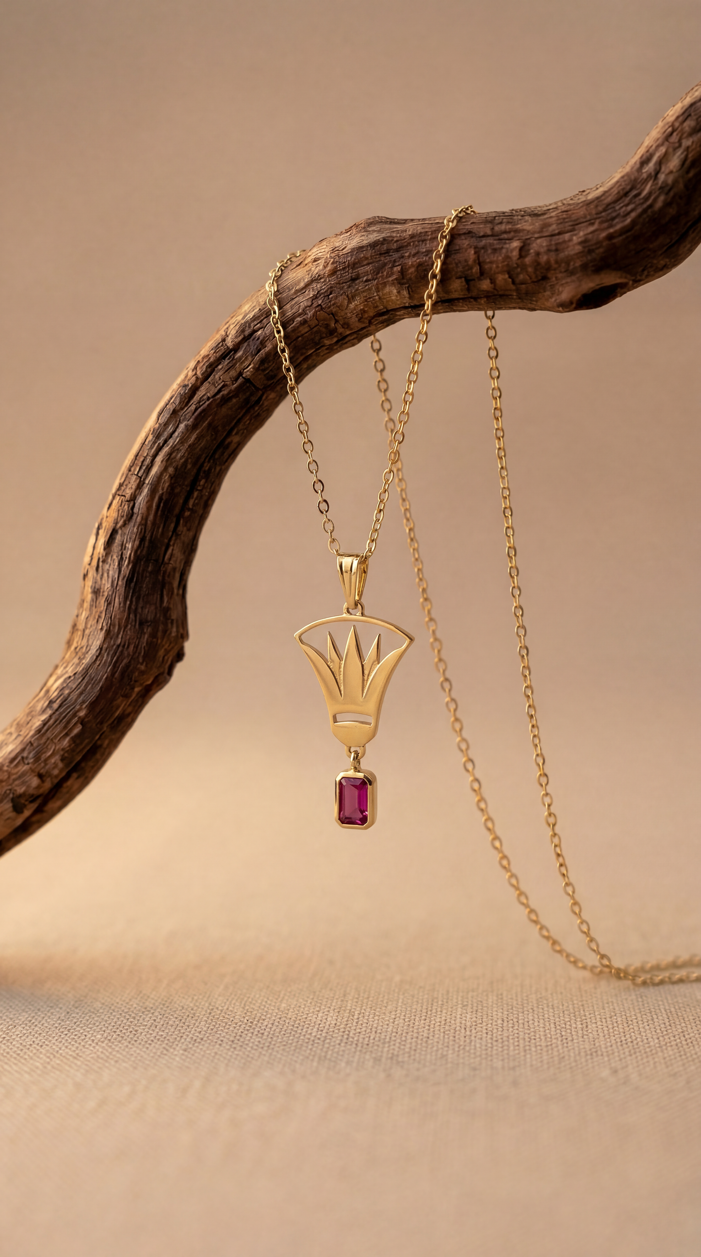 Gold lotus necklace hanging from a wooden branch