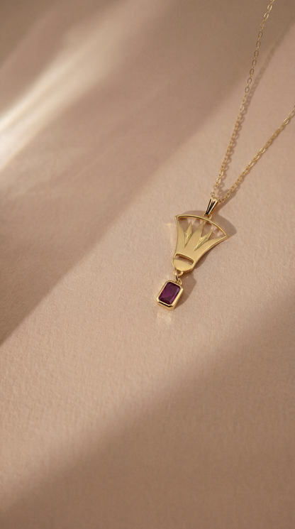 gold lotus necklace with red gemstone on beige background