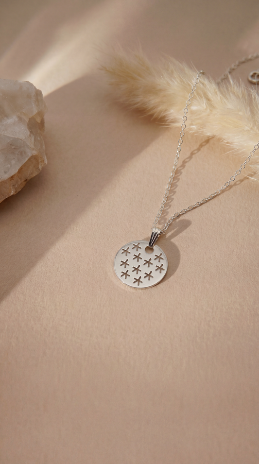 Silver necklace with a star-patterned pendant on a beige background